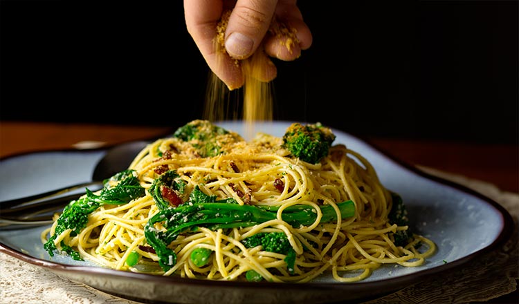 Sprinkling breadcrumbs over pasta with broccoli rabe