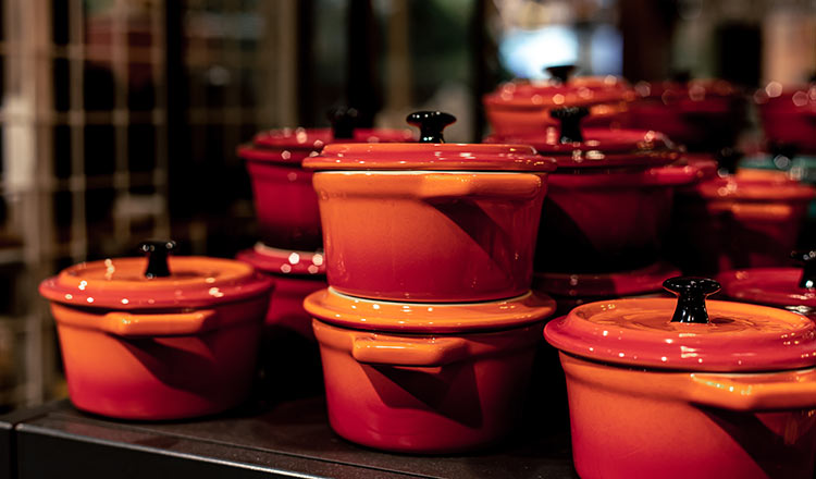 Stacks of red-orange Dutch ovens in a store window