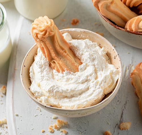 A bowl of over-whipped cream with a cookie dipped in.