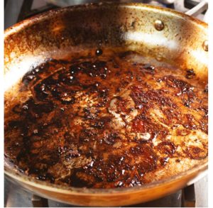 A stainless steel pan with burned pan drippings.