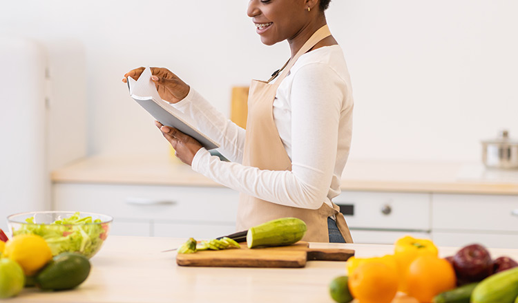 woman in an apron reading a cookbook.