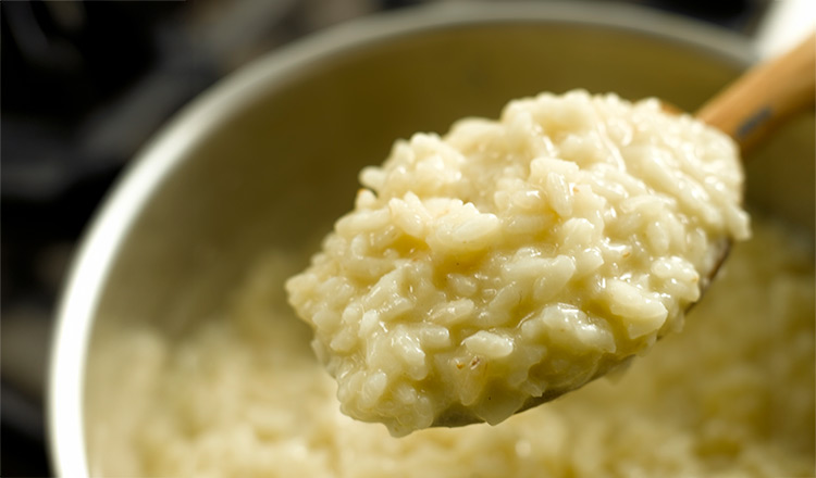 Cooked risotto on a wooden spoon.