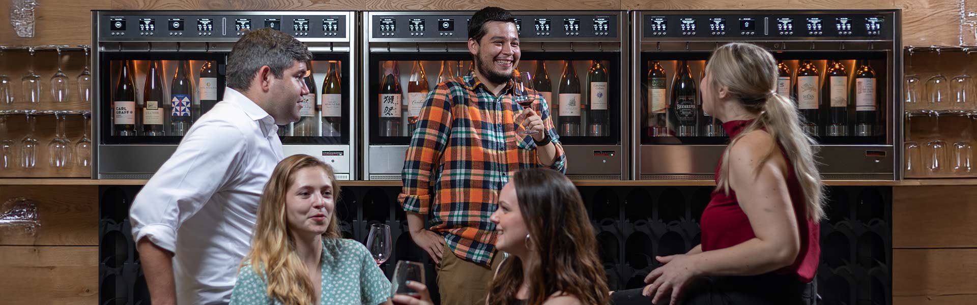 Wine bar with self-serve dispensers and guests enjoying wine in a modern indoor setting at CIA at Copia.