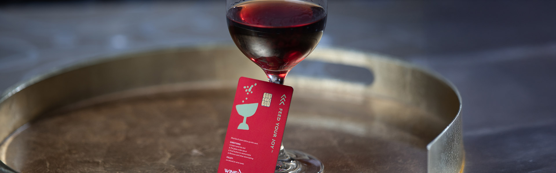 A glass of red wine with a prepaid wine tasting card in CIA at Copia's Wine Bar in Napa, CA.