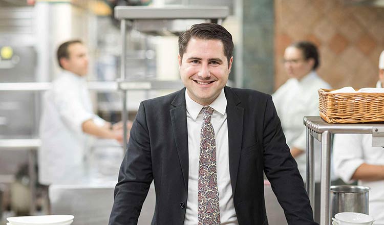 CIA master's student dressed in a suit standing in a kitchen.