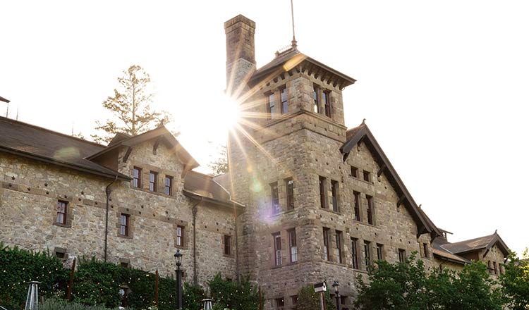 Sunlight peeks around the historic CIA at Greystone stone building in St. Helena, CA.