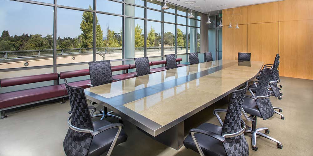 CIA at Copia conference room with a long table, black chairs, wood walls, and Napa River views.