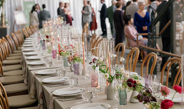 CIA at Copia wedding table set with flowers, candles, and place settings as guests mingle in the background.
