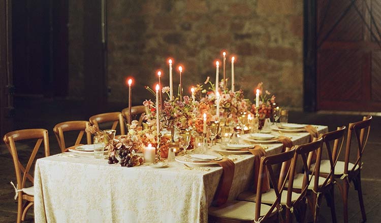 CIA at Greystone banquet table with candles and floral centerpieces in a warm, historic stone room.